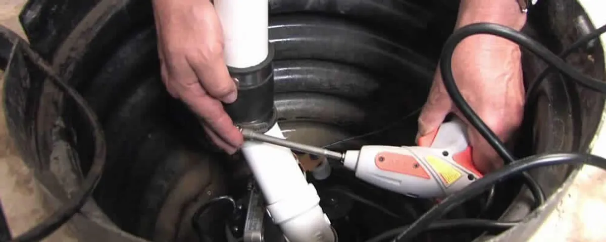Sump pump installation technician connecting PVC discharge piping in Redmond, WA